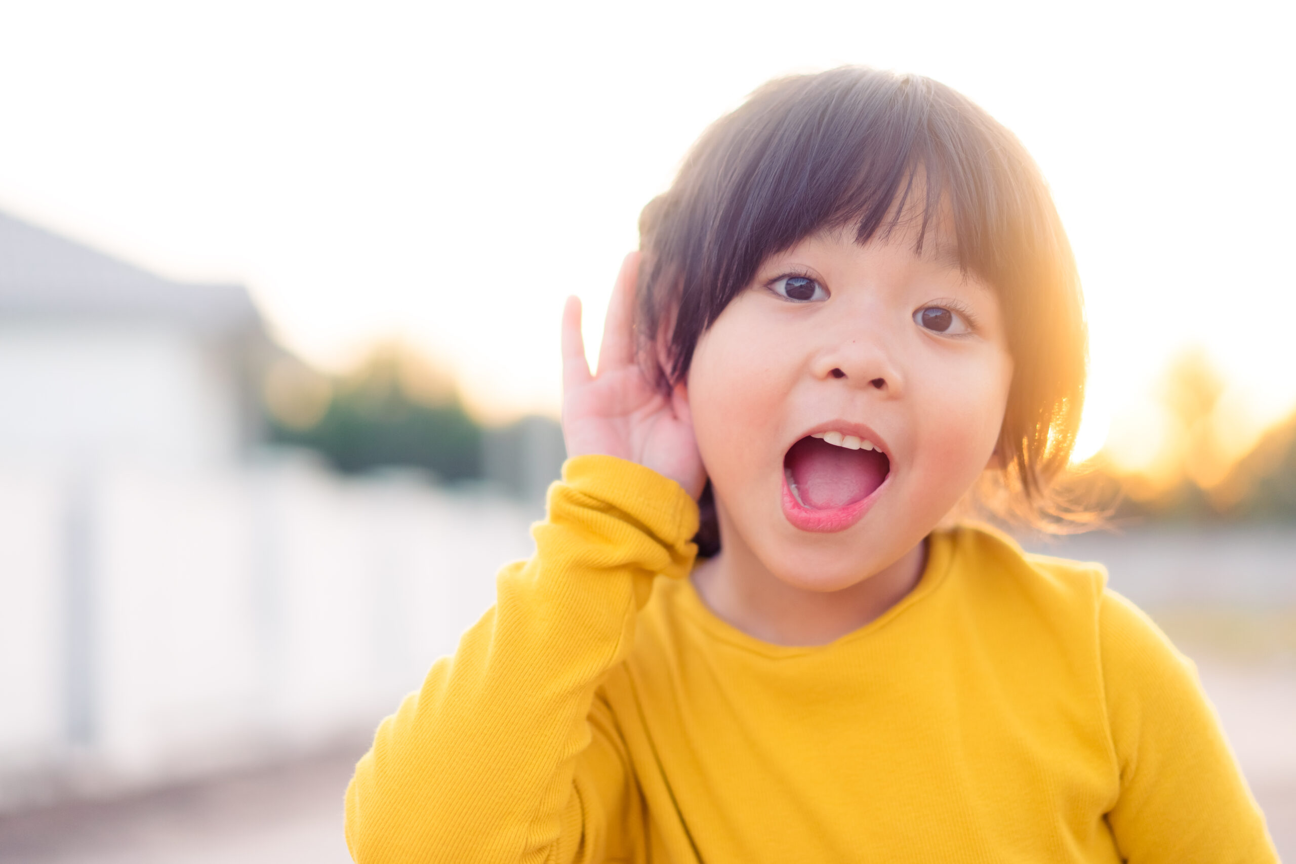 Little,Asian,Girl,Holds,Her,Hand,Near,Her,Ear,And